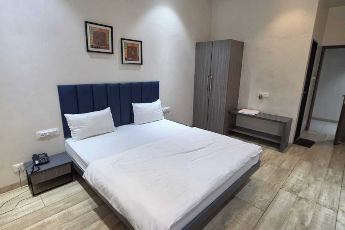 Una habitación de hotel moderna con una cama grande, un armario y una mesita de noche con un teléfono.
