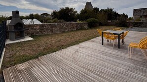 En træterrasse med grill og udendørs møbler.
