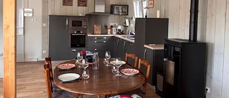 Une cuisine moderne avec un îlot central, des chaises en bois et des luminaires suspendus en rotin.