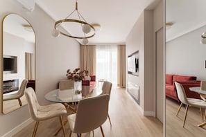 Ein modernes Hotelzimmer mit Essbereich, einer Sitzecke, einem Fernseher und einem großen Spiegel.
