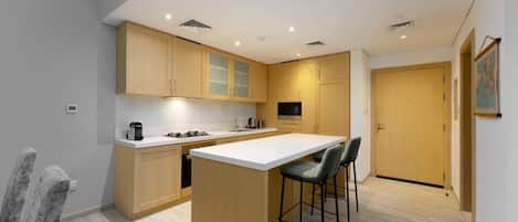 A modern kitchen with a central island, bar stools, and a dining area.
