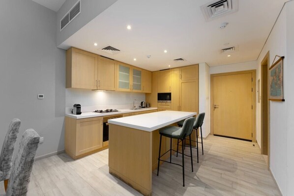 A modern kitchen with a central island, bar stools, and a dining area. - The Belgravia Residence | Refined 1BR in JVC (Jumeirah Village Circle (JVC))