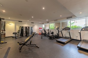 Ein Fitnessstudio mit verschiedenen Trainingsgeräten, darunter Laufbänder und Kraftgeräte, sowie großen Fenstern, die für natürliches Licht sorgen.
