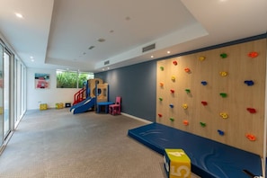Ein Spielbereich für Kinder mit Rutsche, Kletterwand und weichem Spielboden.