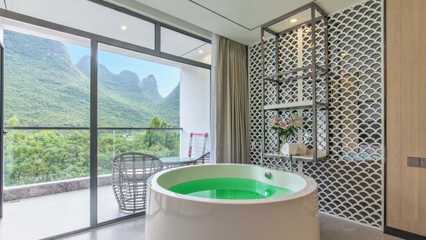 Un baño moderno con una bañera grande, un separador de vidrio y vistas a un paisaje montañoso.