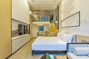 A hotel room with a bed, a sofa, a TV, a staircase, and a balcony.