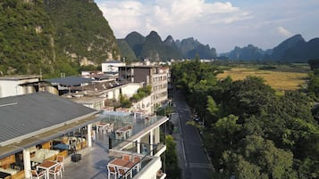 A hotel with outdoor seating overlooking a valley and mountains.
