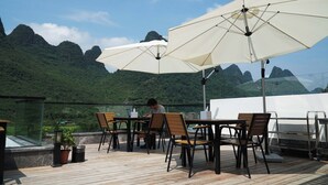 Una terraza con asientos al aire libre, sombrillas y vistas a las montañas.