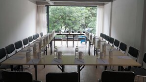 Una sala de conferencias con una larga mesa, sillas, botellas de agua y documentos.