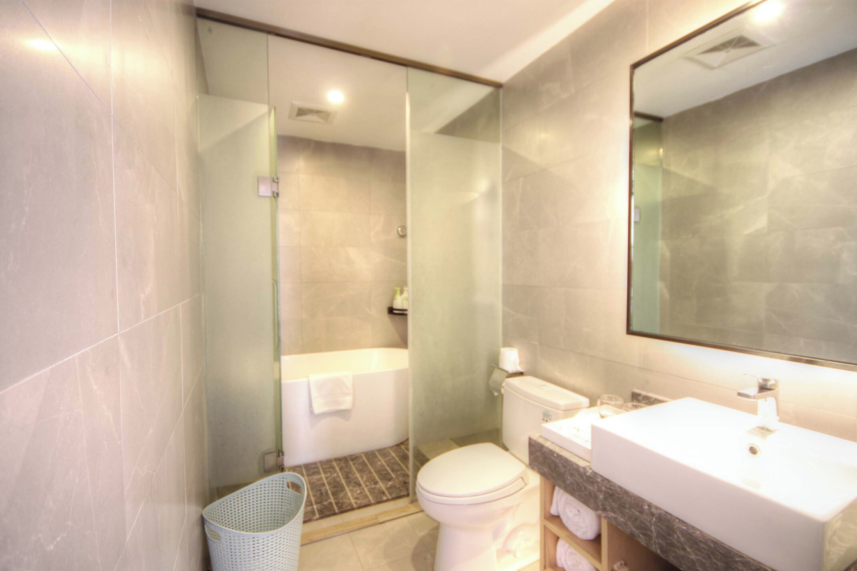 A modern bathroom with a glass shower enclosure, a toilet, and a sink with a marble countertop.