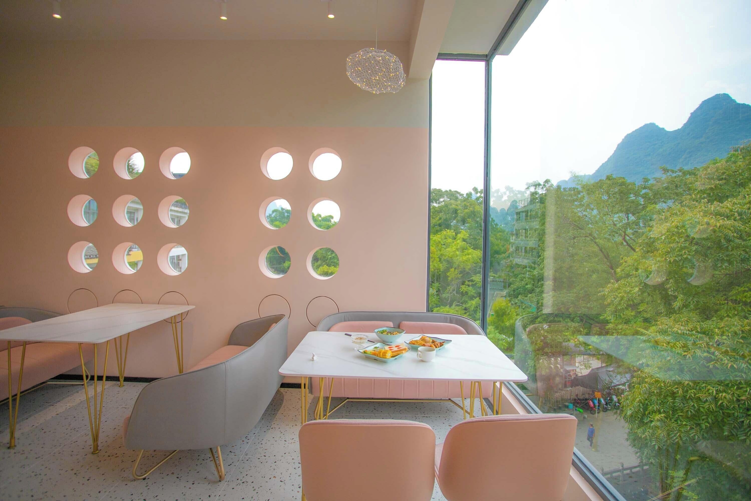 A dining area with a table set for two, chairs, and a wall with circular mirrors.