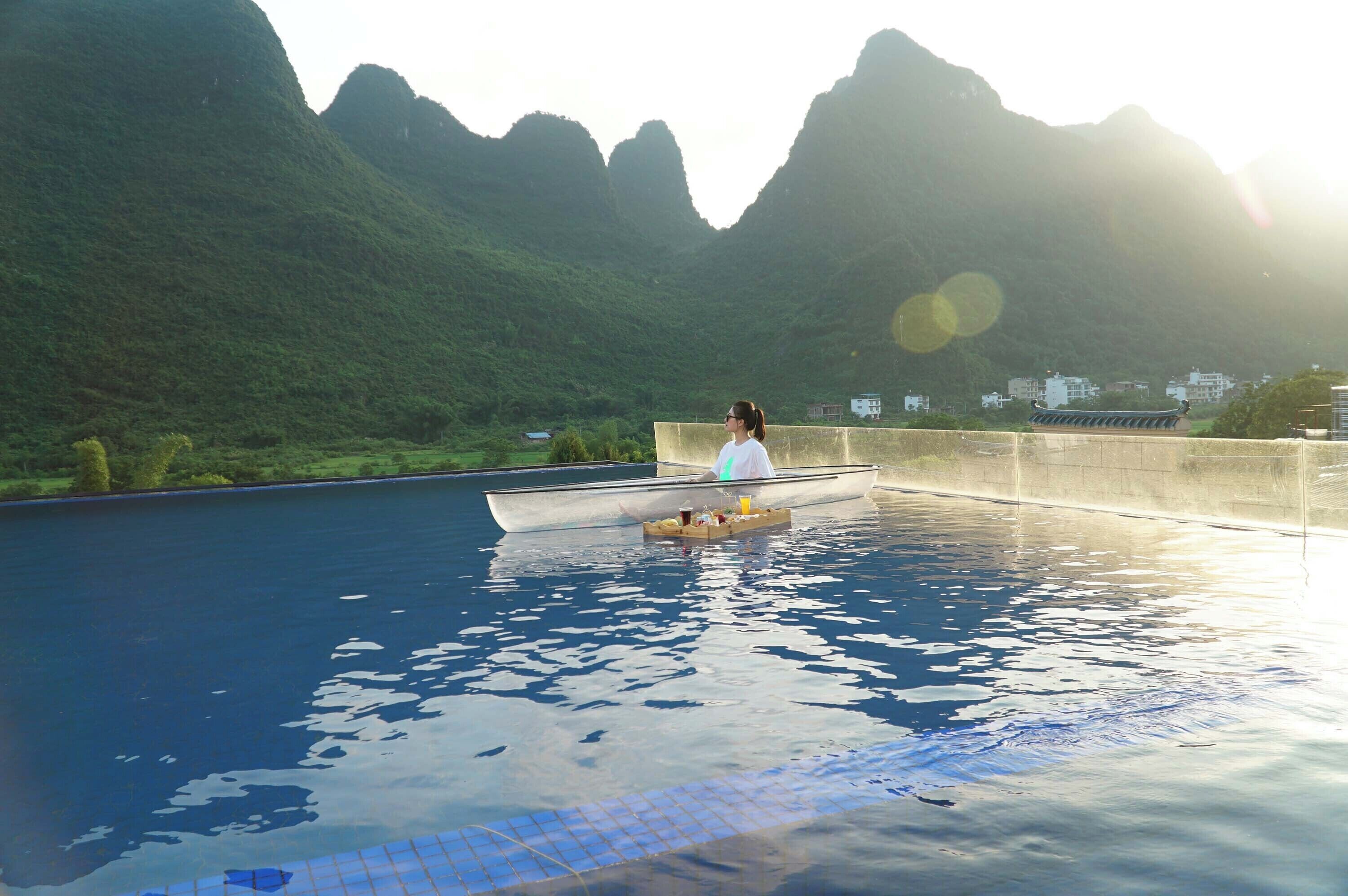 A person in a boat on a pool with a mountainous backdrop.