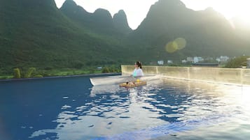 A person in a boat on a pool with a mountainous backdrop.