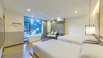 A hotel room with two beds, a sitting area, a large window with a view, and an air conditioning unit.