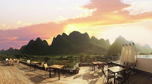 A deck with tables and chairs, overlooking a mountainous landscape. - Liangsu Shili Jiangshan Hotel (Guilin)