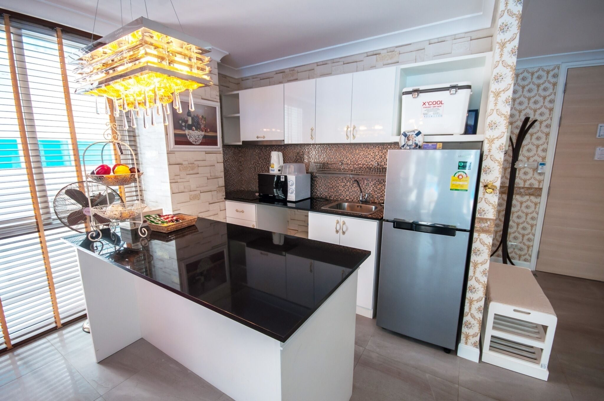 A modern kitchen with a central island, stainless steel appliances, and a decorative hanging light fixture.