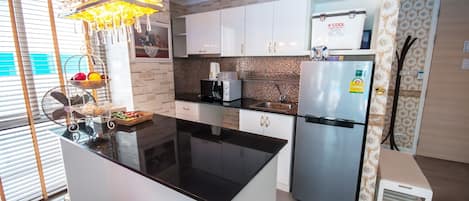 A modern kitchen with a central island, stainless steel appliances, and a decorative hanging light fixture.