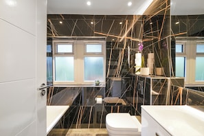 A modern bathroom with black marble walls, a white bathtub, and a toilet. - Charming 3-bedroom house in welcoming London neighborhood (london)