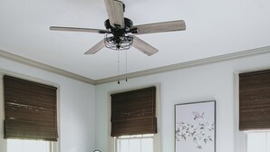 Un dormitorio con cama, cómoda, banco y ventilador de techo.
