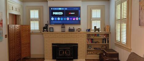 Una sala de estar con chimenea, un televisor en la pared y un sofá.