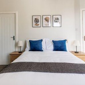 A bedroom with a bed, two nightstands, and three framed pictures on the wall. - 3 Br Home Perfect for big Groups (Darlington)