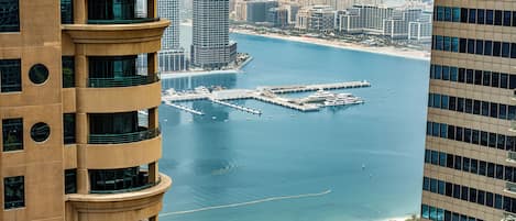 A high-rise building with a marina and a beach in the background.