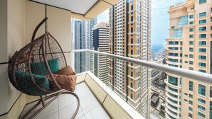Uma varanda com uma cadeira suspensa e vista para edifícios altos.