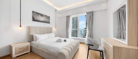 A modern hotel room with a large bed, a desk, and a view of the cityscape.