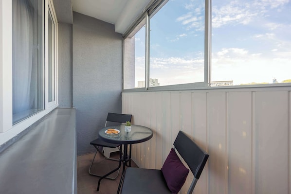 Uma varanda com mesa, cadeiras e vista para o horizonte da cidade.