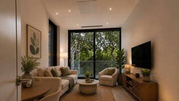 Una sala de estar moderna con un sofá, un sillón, una mesa de centro y un televisor sobre un mueble de madera.