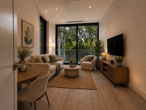A modern living room with a sofa, armchair, coffee table, and a TV on a wooden cabinet. - 1 & 2 Bed Chic Apartments near Battersea Central London FREE WIFI & AIRCON by City Stay Aparts London (London)
