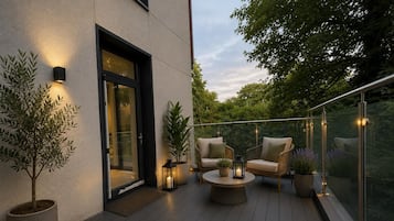 Una terraza con dos sillas, una mesa y plantas en macetas.