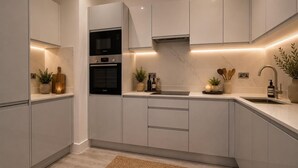 A modern kitchen with white cabinetry, a built-in oven, and a stainless steel sink. - 1 & 2 Bed Chic Apartments near Battersea Central London FREE WIFI & AIRCON by City Stay Aparts London (London)