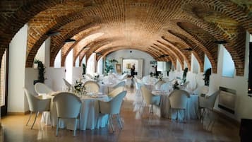 Un espace de restauration intérieur doté de voûtes en briques et de tables recouvertes de nappes blanches.