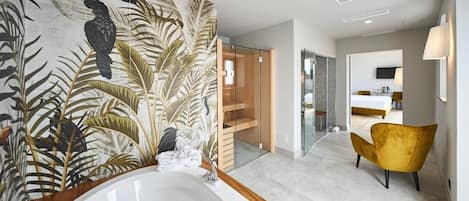 Un baño moderno con una bañera grande, cabina de ducha de vidrio y un sillón amarillo.