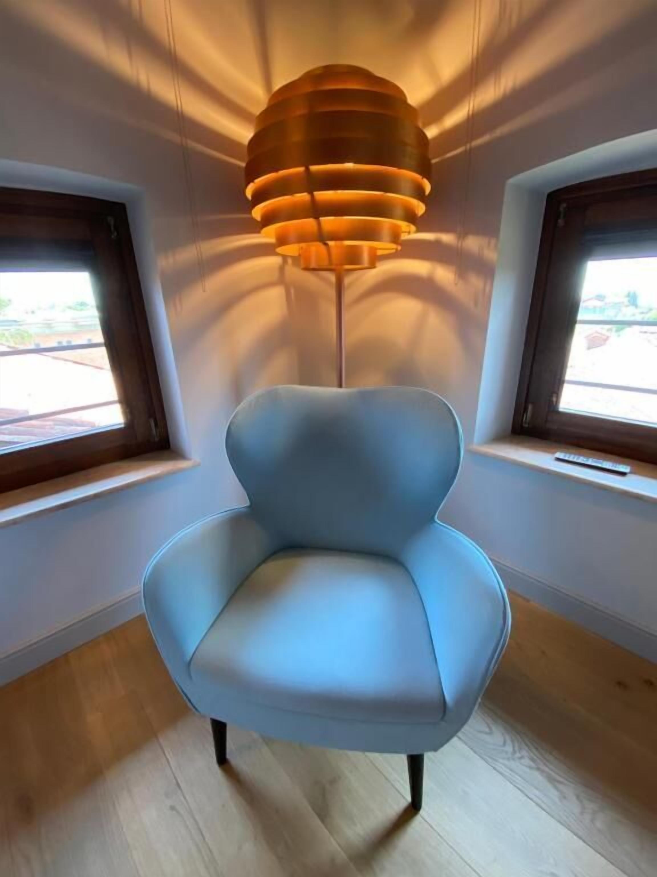 Een moderne stoel met een opvallend ontwerp, geplaatst in een kamer met houten vloer en twee ramen.