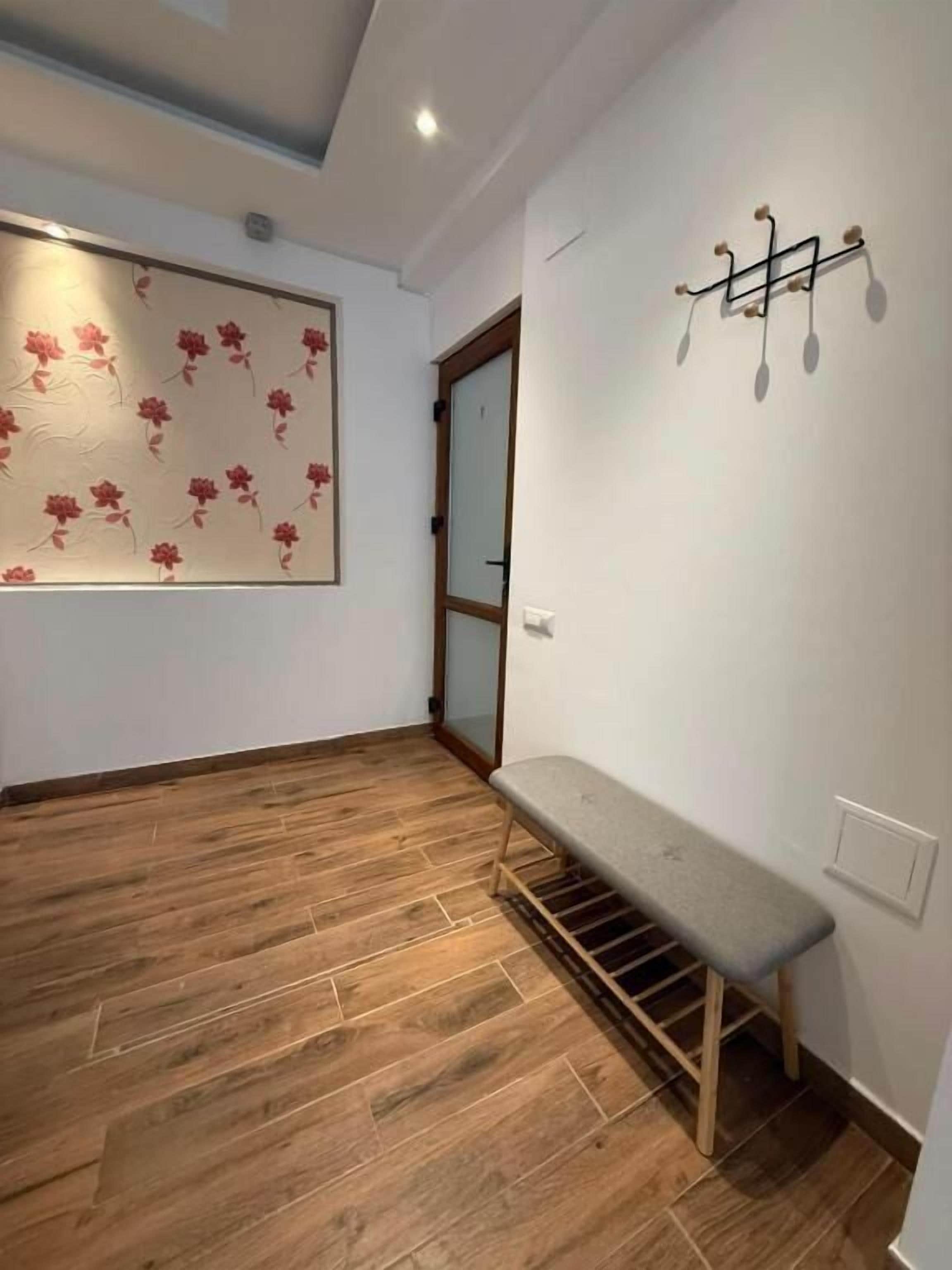Une pièce avec un plancher en bois, un banc, un luminaire fixé au mur et une porte.