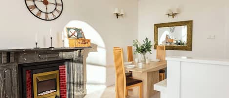 A dining area with a fireplace, a wall clock, and a mirror.