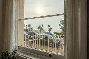 A window with a view of parked cars and palm trees outside. - Sea Views, Free parking & Wi-Fi  Grade 2* Listed (Torbay)