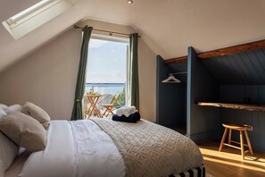 Ein Schlafzimmer mit Bett, Fenster, Sessel und Tisch.