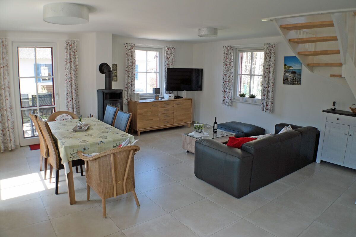 A living room with a sofa, a dining table with chairs, a TV, and a staircase.