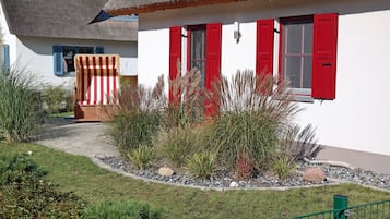 A white building with red shutters and a thatched roof.