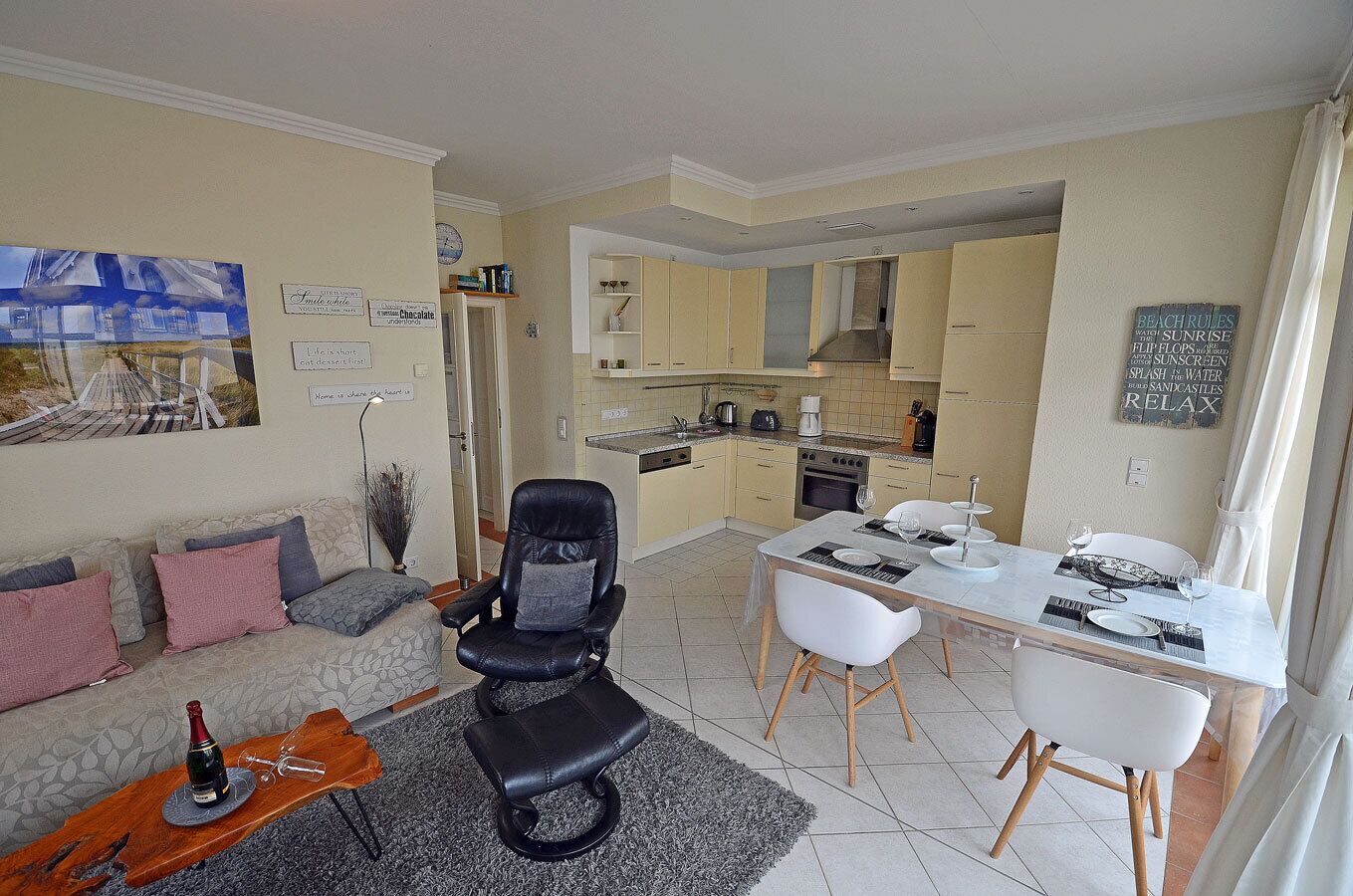 Un salon moderne avec un canapé, un fauteuil en cuir noir et une table à manger dressée pour quatre personnes.