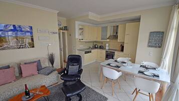 Un salon moderne avec un canapé, un fauteuil en cuir noir et une table à manger dressée pour quatre personnes.