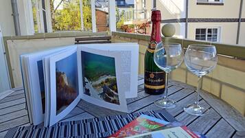 Une table avec une bouteille de vin, deux verres et un livre illustré de paysages.