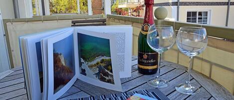 A table with a bottle of wine, two glasses, and a book with images of a landscape.