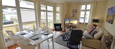 A living room with a dining area, a sofa, and a TV.