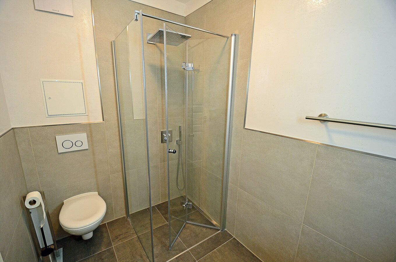 Ein Badezimmer mit Duschkabine, Toilette und Handtuchhalter.