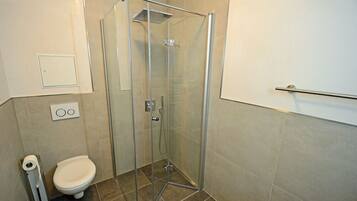 Ein Badezimmer mit Duschkabine, Toilette und Handtuchhalter.