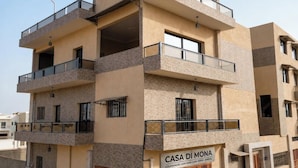 Um edifício residencial de vários andares com varandas, uma placa indicando ser uma cooperativa de saúde e uma entrada com portão.